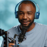 Brayan Olson Podcaster wearing headphones and speaking into a microphone, engaging with the audience in a creative arts and lifestyle podcast episode.