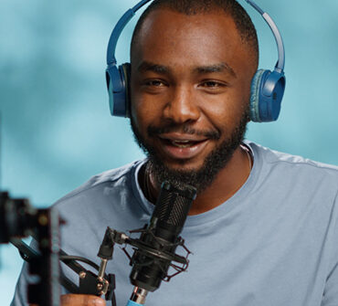 Smiling audio host wearing headphones and speaking into a microphone, representing the Blueprints and Beginnings platform.