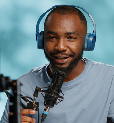 Brayan Olson, podcast host, wearing headphones and speaking into a microphone, showcasing his engaging personality in a recording studio setting.
