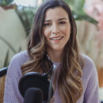 Jessica Jung smiling while seated in front of a microphone, discussing fashion and lifestyle topics for the podcast "Everything looks so tiny from up here."
