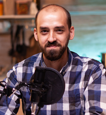 Mike Hardson, podcast host, smiling in a checkered shirt with a microphone, showcasing his role in connecting with listeners.
