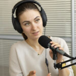 Jessica Jung Woman wearing headphones speaking into a microphone, engaging in a podcast discussion about lifestyle and fashion topics.