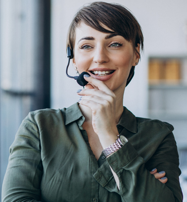 Sarah Albert, podcast host and manager, smiling while wearing a headset in a modern office setting.