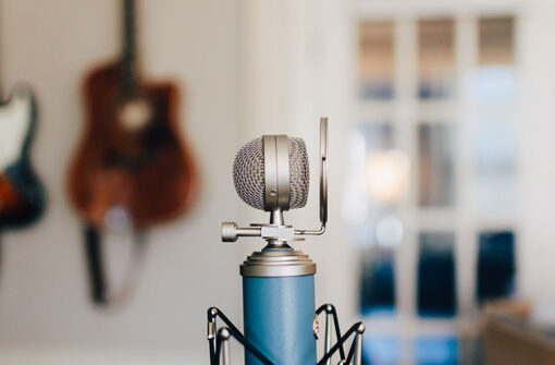 Microphone in focus with blurred guitars in the background, symbolizing audio content creation for photography discussions.