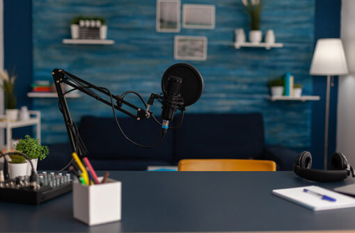 Podcast recording setup featuring a microphone, audio mixer, and workspace with a blue wall backdrop, relevant to music-related podcasts.